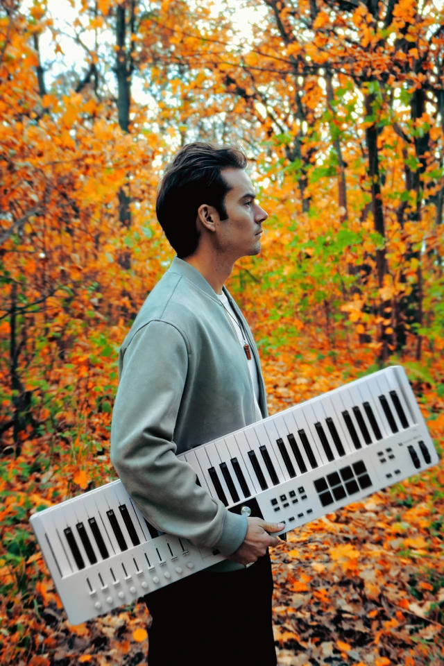 engimono in profile holding a keyboard in an autumn forest